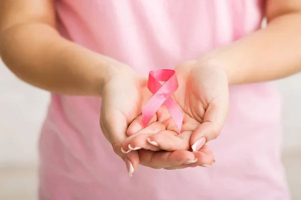 Menina irreconhecível segurando fita rosa sobre fundo branco, cortado — Fotografia de Stock