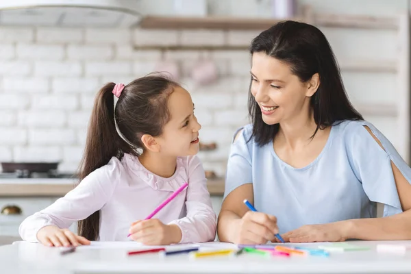 Fille mignonne et jeune mère dessinent ensemble dans la cuisine — Photo