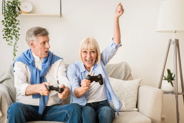 Pareja mayor pasar un buen rato, jugando videojuegos — Foto de Stock