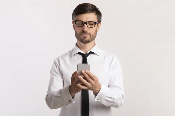 Seriöser Geschäftsmann mit Smartphone auf weißem Hintergrund — Stockfoto