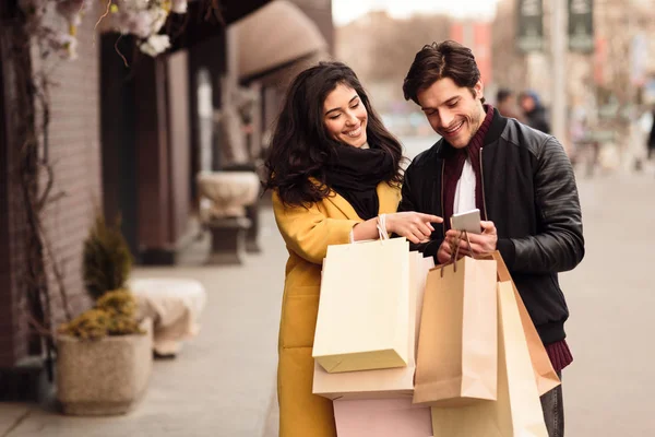 Jovem casal andando depois de fazer compras e chamar táxi — Fotografia de Stock