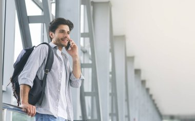 Havaalanında cep telefonuyla konuşan genç adam yolcu