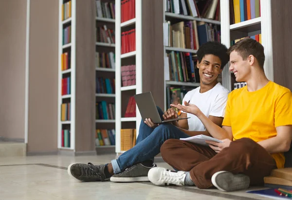 Dos chicos jóvenes divirtiéndose mientras estudian en la biblioteca — Foto de Stock