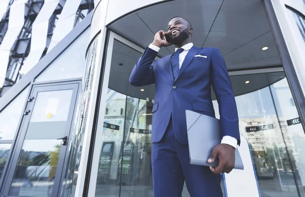 Afro obchodník hovor v telefonu proti vchodu do budovy kanceláře — Stock fotografie