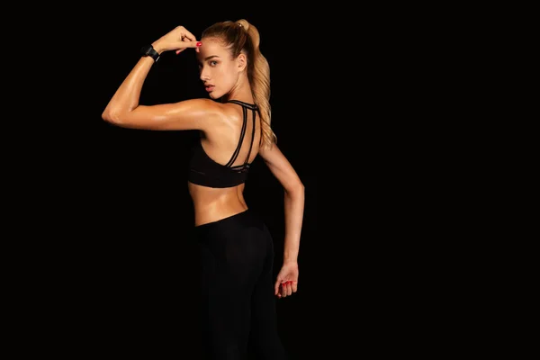 Fit Mädchen zeigt Armmuskeln posiert über schwarzem Hintergrund — Stockfoto