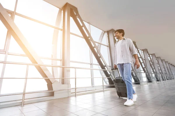 Fröhlicher Mann läuft mit Gepäck im Flughafenterminal — Stockfoto