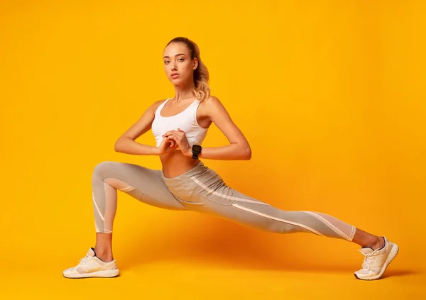 Meisje doet Deep Lunge oefening over gele achtergrond — Stockfoto