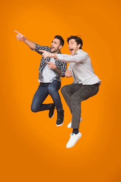 Podekscytowany mężczyźni wskazując palce od, skoki przez studio tło — Zdjęcie stockowe