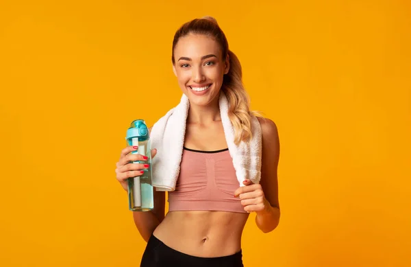 Fitness-Mädchen mit Wasserflasche posiert auf gelbem Hintergrund — Stockfoto