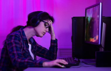 Sıkılmış kadın oyuncu bilgisayarda video oyunları oynuyor