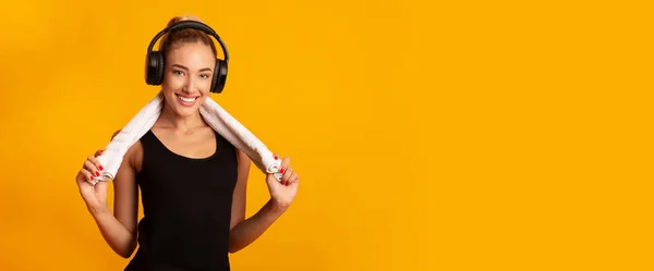 Menina positiva em fones de ouvido segurando toalha de pé no estúdio, Panorama — Fotografia de Stock