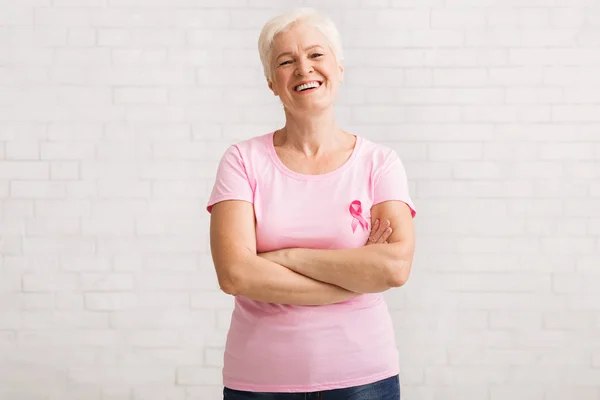 Ανώτερη γυναίκα σε ροζ καρκίνο του μαστού T-shirt στέκεται πάνω από το λευκό τοίχο — Φωτογραφία Αρχείου