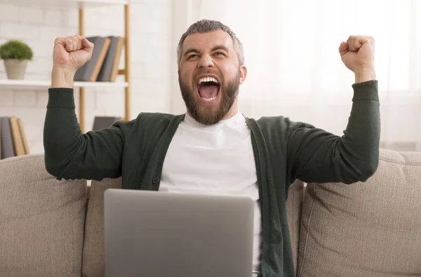 Opgewonden bebaarde man viert succes in de voorkant van de laptop — Stockfoto