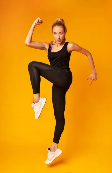 Menina desportiva saltando exercício no fundo amarelo — Fotografia de Stock