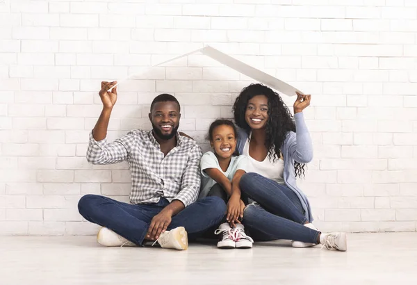 African American Family Sitting Under Roof Dreaming Of New Home.