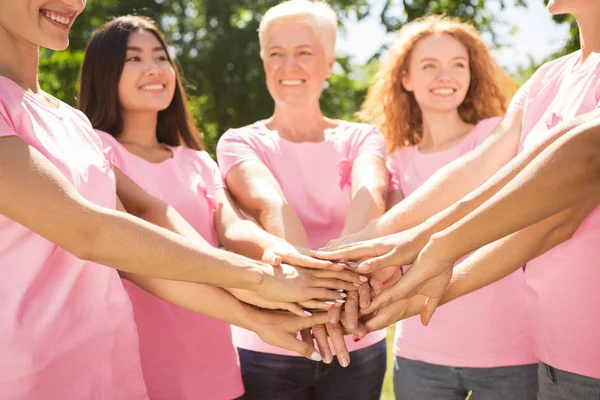 Diverse Women Wearing Breast Cancer Ribbon T-Shirts Holding Hands
