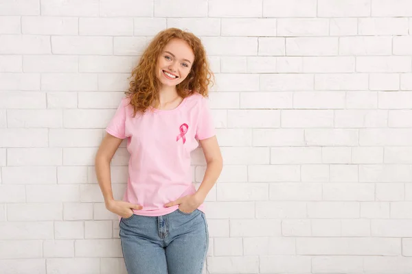 Voluntaria chica en rosa cinta camiseta de pie sobre la pared blanca — Foto de Stock