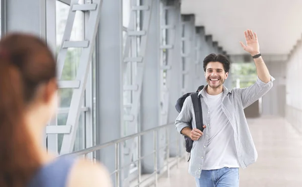 Cheerful tourist greeting his friend, waving hand at airport walkway — Stock Photo, Image