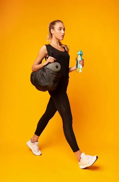 Chica va al gimnasio sosteniendo bolsa y botella de agua, estudio — Foto de Stock