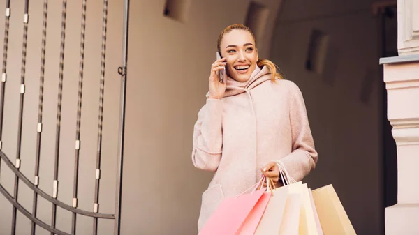 Jovem mulher falando ao telefone depois de fazer compras em boutiques — Fotografia de Stock