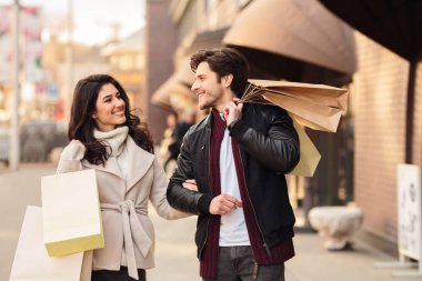 Mutlu shopaholics alışveriş yaptıktan sonra alışveriş torbaları ile yürüyüş