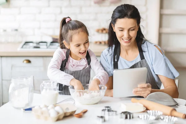 Matka a dcera používají digitální tablet v kuchyni, hledají recept — Stock fotografie