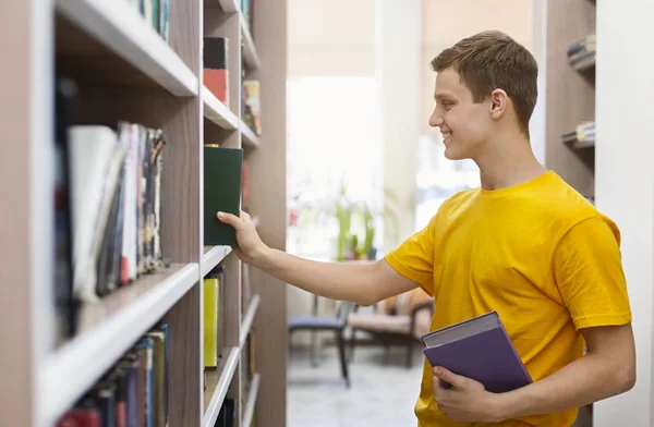 Jovem bonito escolhendo livros na livraria — Fotografia de Stock