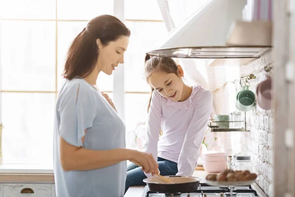 Jovem mãe feliz e filha cozinhar juntos na cozinha — Fotografia de Stock