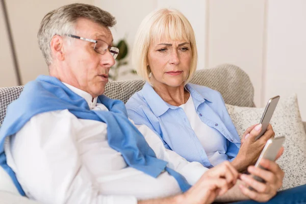 Senior couple learning to use modern phones at home