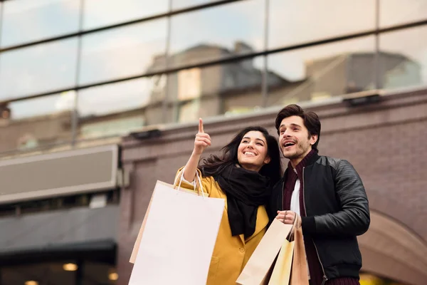 Millennial happy couple shopping together in new city and walking