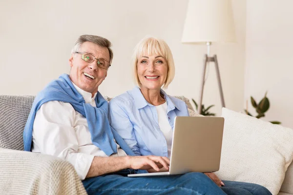 Счастливая зрелая пара с ноутбуком компьютер улыбается в камеру — стоковое фото
