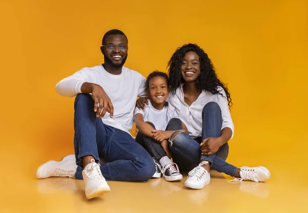 Retrato de família negra feliz sorrindo sobre o fundo do estúdio amarelo — Fotografia de Stock