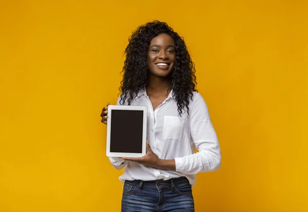 Vrolijke zwarte vrouw die blanco digitale tablet scherm demonstreert — Stockfoto