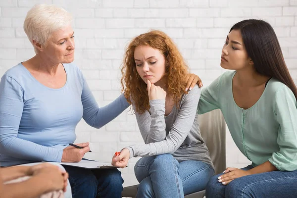 Diversas mujeres apoyando a una chica deprimida en sesión de terapia de grupo en interiores — Foto de Stock