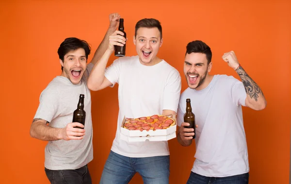 Companheiros alegres bebendo cerveja e comendo pizza, fundo laranja — Fotografia de Stock