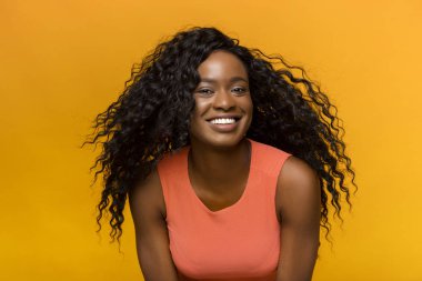Çekici Afrikalı kız sarı arka plan üzerinde kamera poz