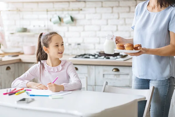 Mutter bringt Muffins und Milch, um ihre Tochter zu füttern — Stockfoto