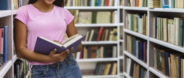 Afro girl holding open book, leaning on bookshelf clipart