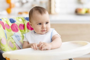 Mutfakta mama sandalyesinde oturan sevimli bebek