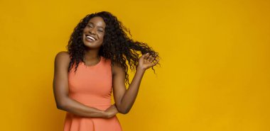 Parlak elbiseli güzel afrikalı kız saçlarıyla oynuyor