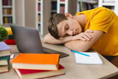 Dizüstü bilgisayarın önünde işyerinde uyuyan yorgun öğrenci