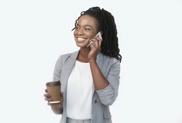 Lachende Afro zakenvrouw praten op mobiele telefoon houden koffie kopje, witte achtergrond — Stockfoto