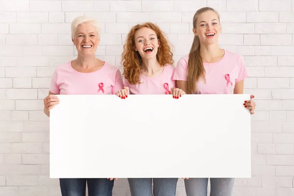 Kobiety w piersi cancer T-shirty Holding White Board przed Wall — Zdjęcie stockowe