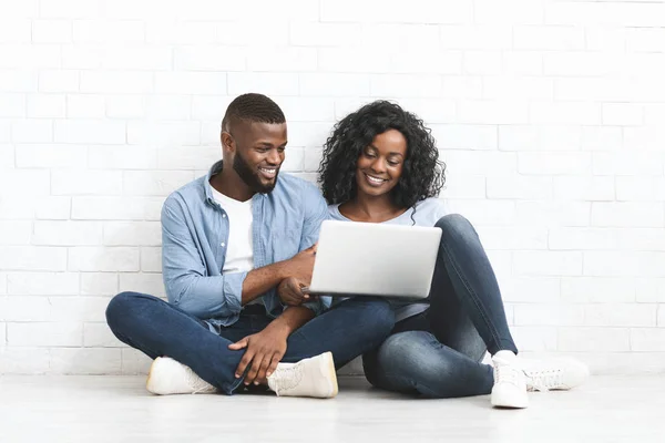 Ευτυχισμένο ζευγάρι κάθεται στο πάτωμα, χρησιμοποιώντας το laptop σε νέο σπίτι — Φωτογραφία Αρχείου
