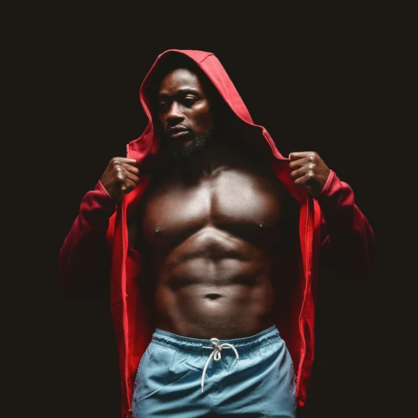 Afrikanischer Boxer in rotem Kapuzenpulli über schwarzem Studiohintergrund — Stockfoto