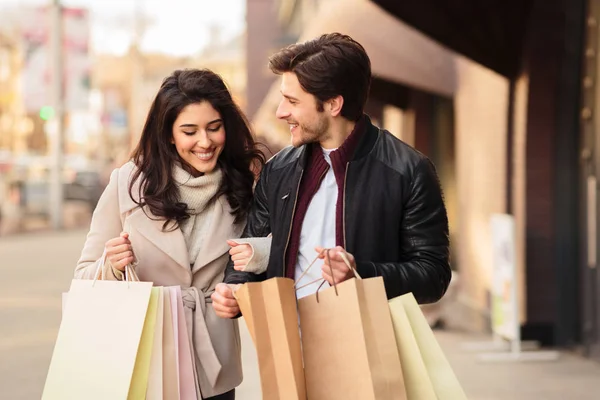 Jovens shopaholics olhando em sacos de compras ao ar livre — Fotografia de Stock