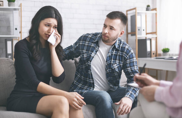Emotional woman crying at therapy session with psychologist