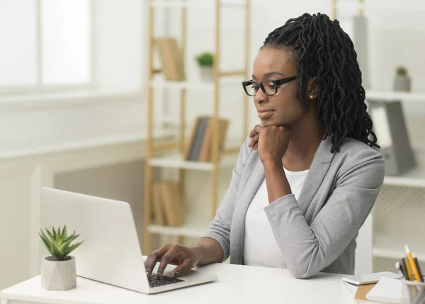 Pensativo Afro Businesswoman escribiendo en el ordenador portátil en la oficina moderna —  Fotos de Stock