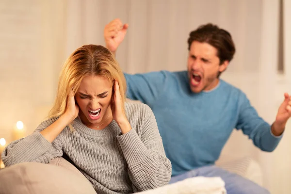 Abuso marido gritando a su esposa sentada en el sofá en casa —  Fotos de Stock