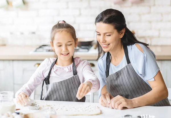 Menina bonita e sua mãe atraente preparando pastelaria juntos — Fotografia de Stock